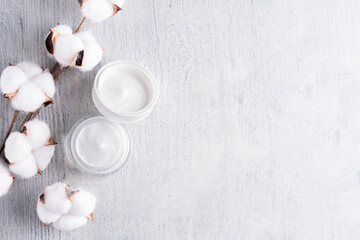 on a gray wooden background, face cream with cotton