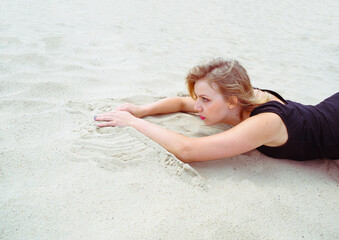 Young woman lying on the sand in a swimsuit looks into the distance. Relax on the beach