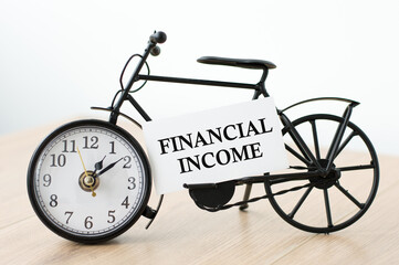 Financial income text on a business card next to a clock on the table, business concept