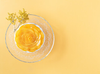 Three milks dessert decorated with peaches on yellow background. Copy space. Top view.