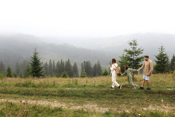 Young mom, dad with daughter travelling. parent playing and running with child outdoors, family trip in mountains. Active summer holidays. mothers, fathers and baby's day concept