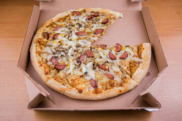 pizza with sausages and mushrooms in a cardboard box cheese