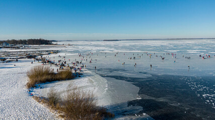 Aerial view of people ice skating on a frozen river. Drone shot. 