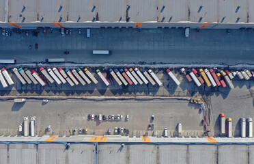 Aerial view of goods warehouse. Logistics center in industrial city zone from above. Aerial view of trucks loading at logistic center. View from drone.