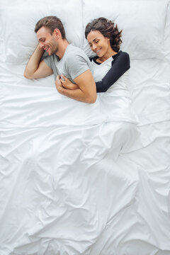 Above View Of Young Romantic Couple Hugging In Bed While Sleeping