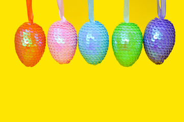 Decorative Easter shiny eggs with sequins on a yellow background. Easter greeting Card. Banner.