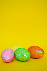 Decorative Easter shiny eggs with sequins on a yellow background. Easter greeting Card. Banner.