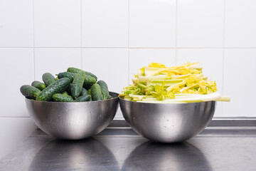 Photo of two bowls, one full of cucumbers and the other with celery, both washed.
