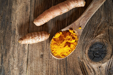Turmeric powder and fresh root on a table, top view