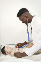 Obraz na płótnie Canvas Black doctor. Baby in diaper. African with stethoscope.