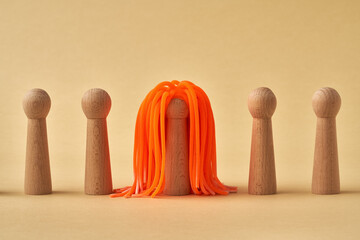 Wooden figures standing in a row, one with long orange hair