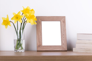 Breakfast still life., empty picture frame mockup on wooden desk, table. Vase with daffodils branches. Elegant working space, home office concept. Scandinavian interior design