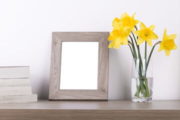 Breakfast still life., empty picture frame mockup on wooden desk, table. Vase with daffodils branches. Elegant working space, home office concept. Scandinavian interior design