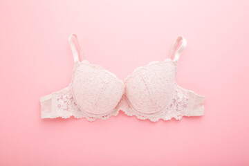 Lace bra on light pink table background. Pastel color. Closeup. Daily female underwear. Top down view. - obrazy, fototapety, plakaty