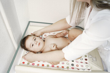 Obraz na płótnie Canvas Woman with stethoscope. Baby in diaper. Baby lying on tummy.