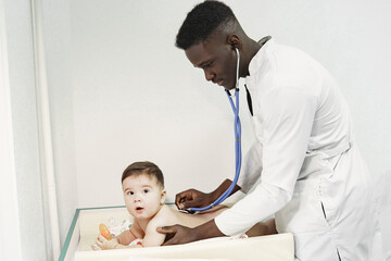 Fototapeta premium Black doctor. Baby in diaper. African with stethoscope.