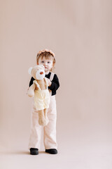 Fototapeta premium My favorite toy. Cute little 2 years old girl hugging her teddy bear and smiling, decorated beige studio background