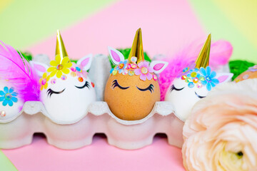 white Easter eggs decorated in the form of unicorns on a colorful background with ranunculus flowers, a minimal creative concept of a happy Easter