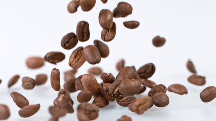 Falling Roasted Coffee Beans on White Background, close-up.