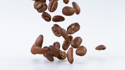 Falling Roasted Coffee Beans on White Background, close-up.