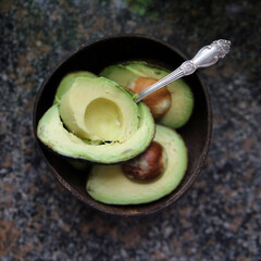 Cut avocado in a coconut bawl on a granite table. Healthy food. 