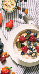 Oatmeal porridge in ceramic bowl with fresh ripe berries  over rustic  background.Top view.
