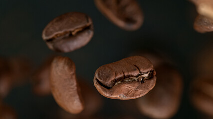 Falling Roasted Coffee Beans on Brown Background, macro shot, close-up.