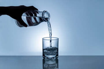 Water is poured from a bottle into a glass. Splashing water. Bottle in hand. Water in a glass. concept High quality photo
