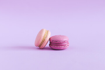 Fototapeta premium Tasty french macarons on a violet pastel background. Pink and violet macarons.