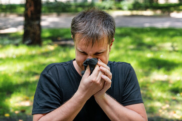 A man sneezes in a grove. Allergy concept