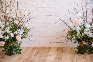 Decorations of branches with beautiful pink and white flowers in the basket against the background of a white brick wall