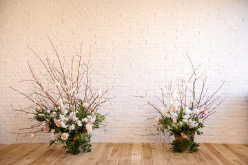 Fototapeta na wymiar Decorations of branches with beautiful pink and white flowers in the basket against the background of a white brick wall
