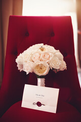 An elegant wedding bouquet of ivory peony roses, a diamond engagement ring and a 