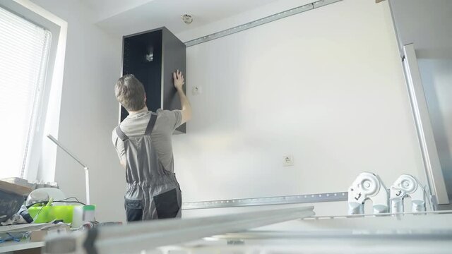 Carpenter assemble kitchen furniture on the wall 4K