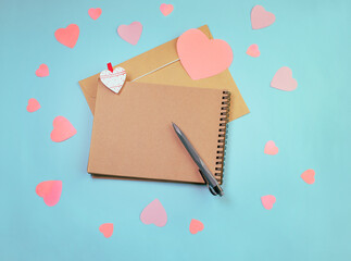 Flatlay notepad mock up with a envelope with hearts on a blue background. Concept of valentine's day and writing love letters