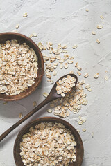 .Whole oat flakes in wooden bowls on a light cement background - 419720877