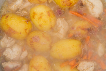Chicken fried with potatoes and vegetables in a cauldron on the grill