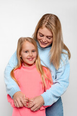 Shot of a happy cheerful mom hugging her little daughter with love against white basckground