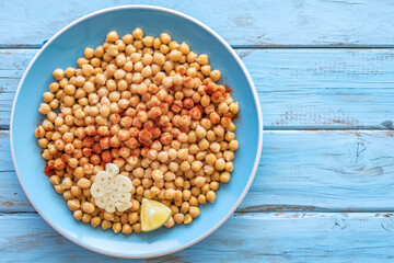 Boiled spiced chickpeas on blue plate over rustic background.