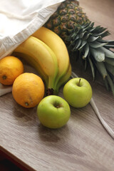 Linen tote bag with pineapple, bananas, lemons and apples. Selective focus.