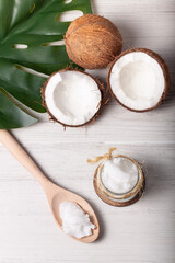 Fototapeta na wymiar Bodegón de dos cocos, uno de ellos cortado por la mitad, con un tarro de aceite de coco y una cuchara de madera