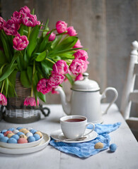 Fototapeta na wymiar colorful eggs and rose tulips, cup of tea over white wood table