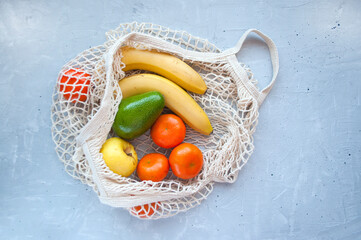 Eco bag with fresh delicious fruits on grey concrete background. Eco friendly concept.