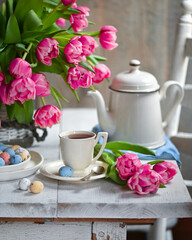 Fototapeta na wymiar colorful eggs and rose tulips, cup of tea over white wood table