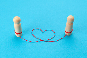Love forever. A heart-shaped thread connects the figures of two people in love on a blue background.
