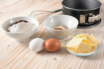 Ingredients for a cake like flour, eggs, butter and sugar on a wooden table, baking at home...