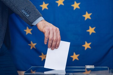 Man putting a ballot into a voting box - European Union. Elections to the European Parliament.