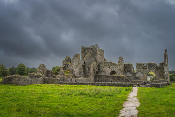 Footpath leading to old ruins of Hore Abbey with dark dramatic storm sky. Located next to Rock of Cashel castle, County Tipperary, Ireland