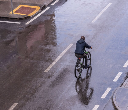 A Man Is Riding A Bike In The Rain. Top View