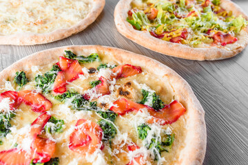 Assortment of pizza with red fish, spinach, parmesan cheese, mozzarella, lettuce, ham, four cheeses.